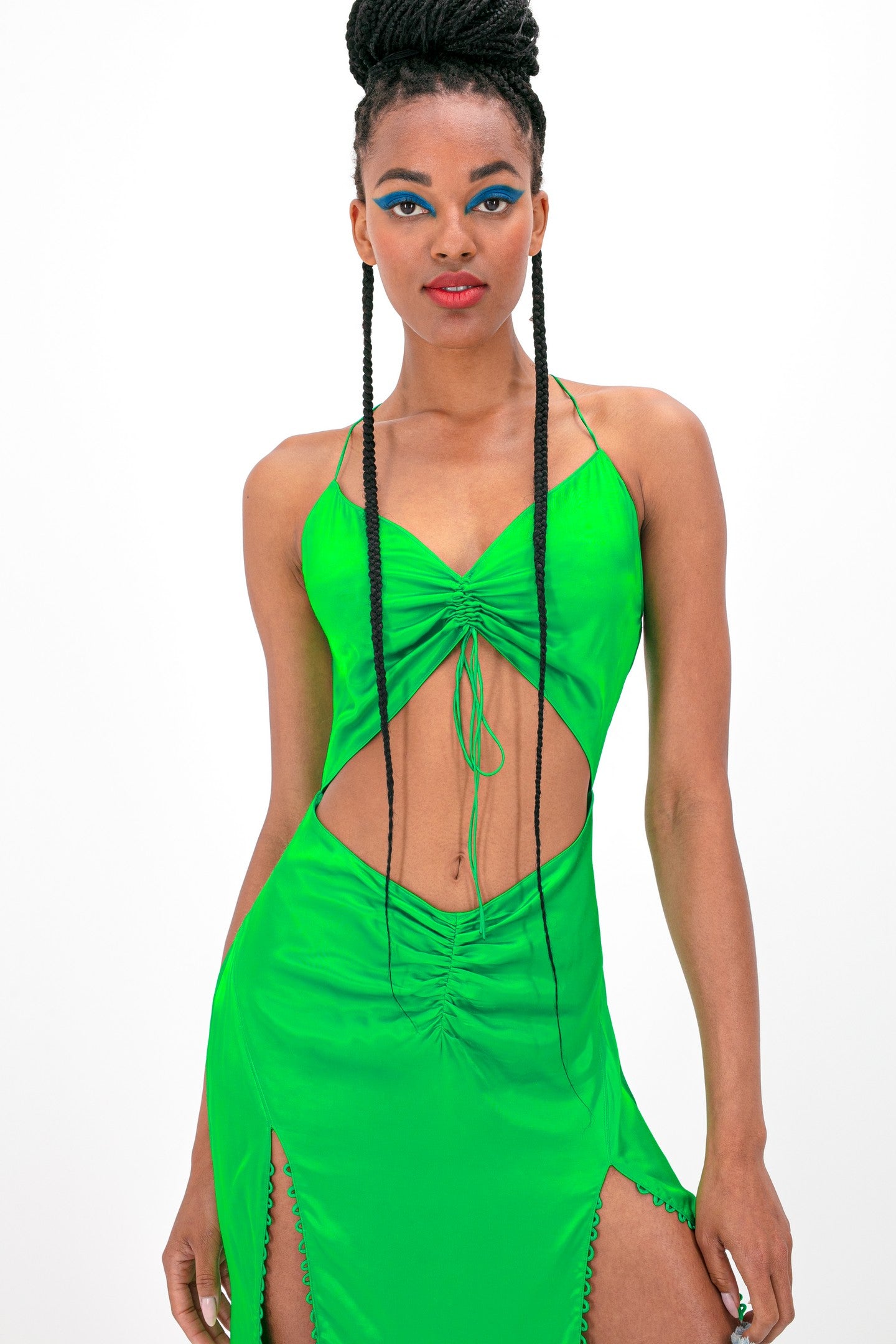 Woman wearing green Andromeda dress against white background, front view, close-up shot, upper body