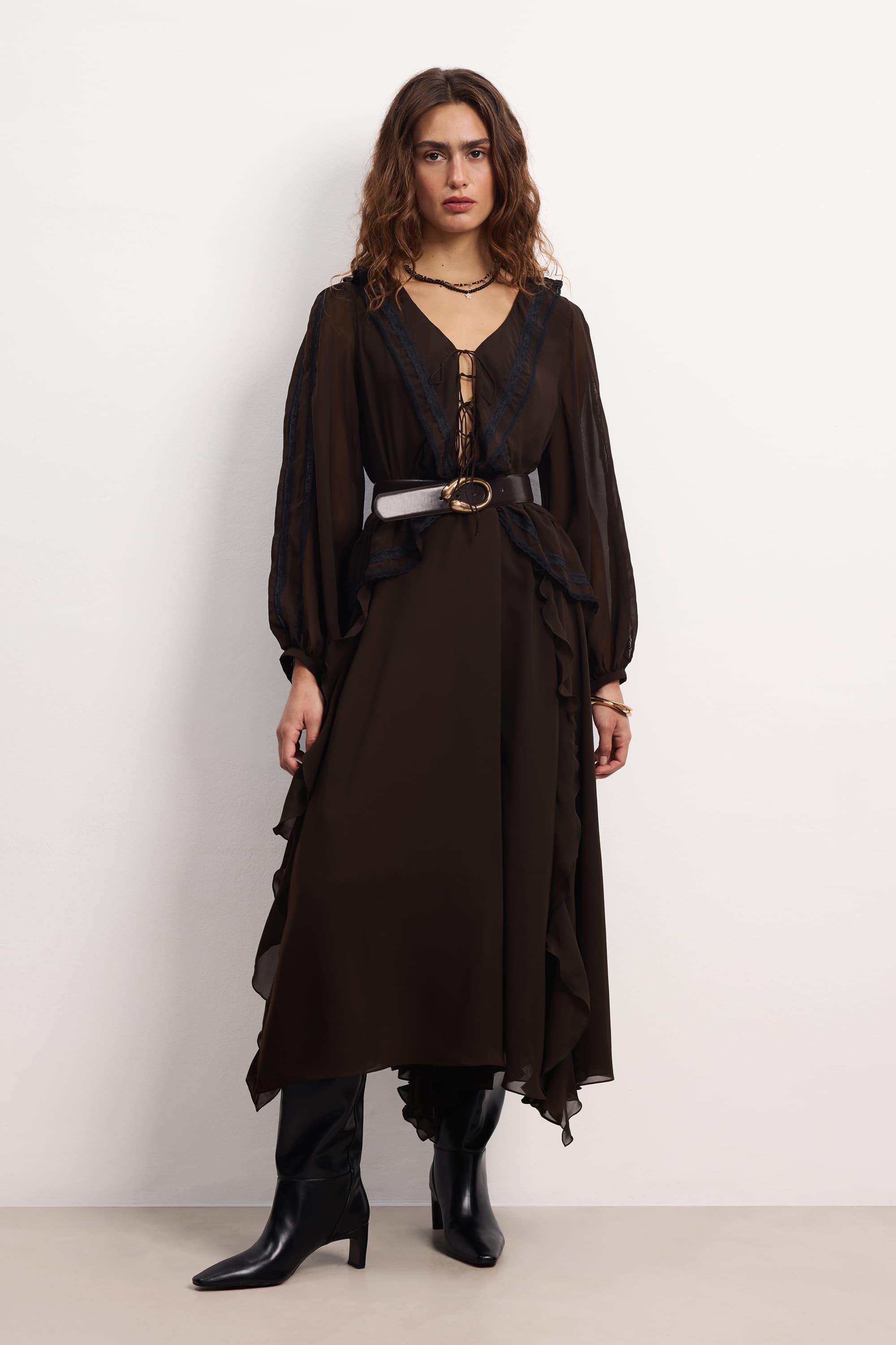 Woman wearing a long black Midnight dress with sheer sleeves against a white background