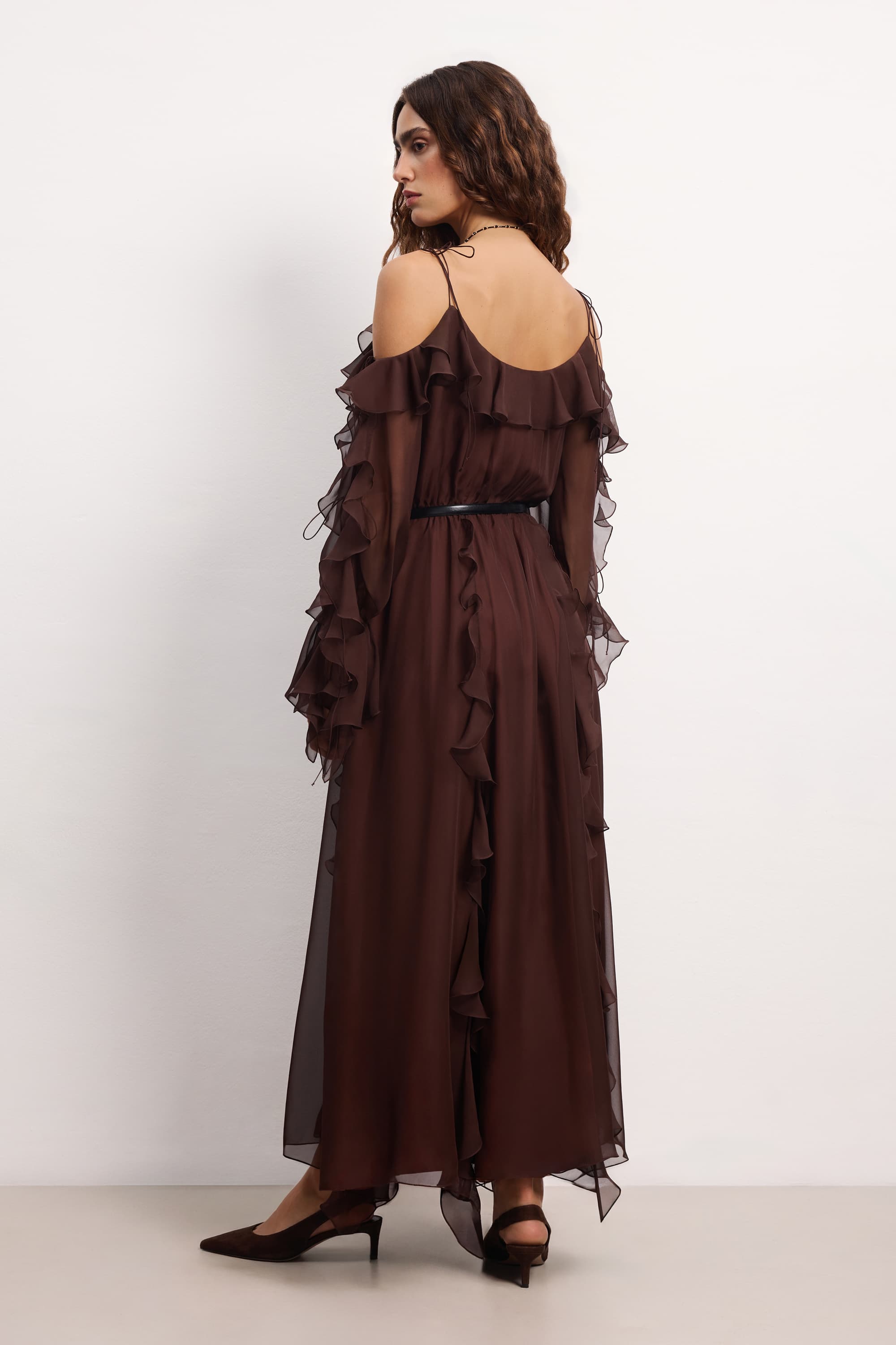 Woman wearing a brown off-shoulder ruffled Morning Forest midi dress on a white background, back view